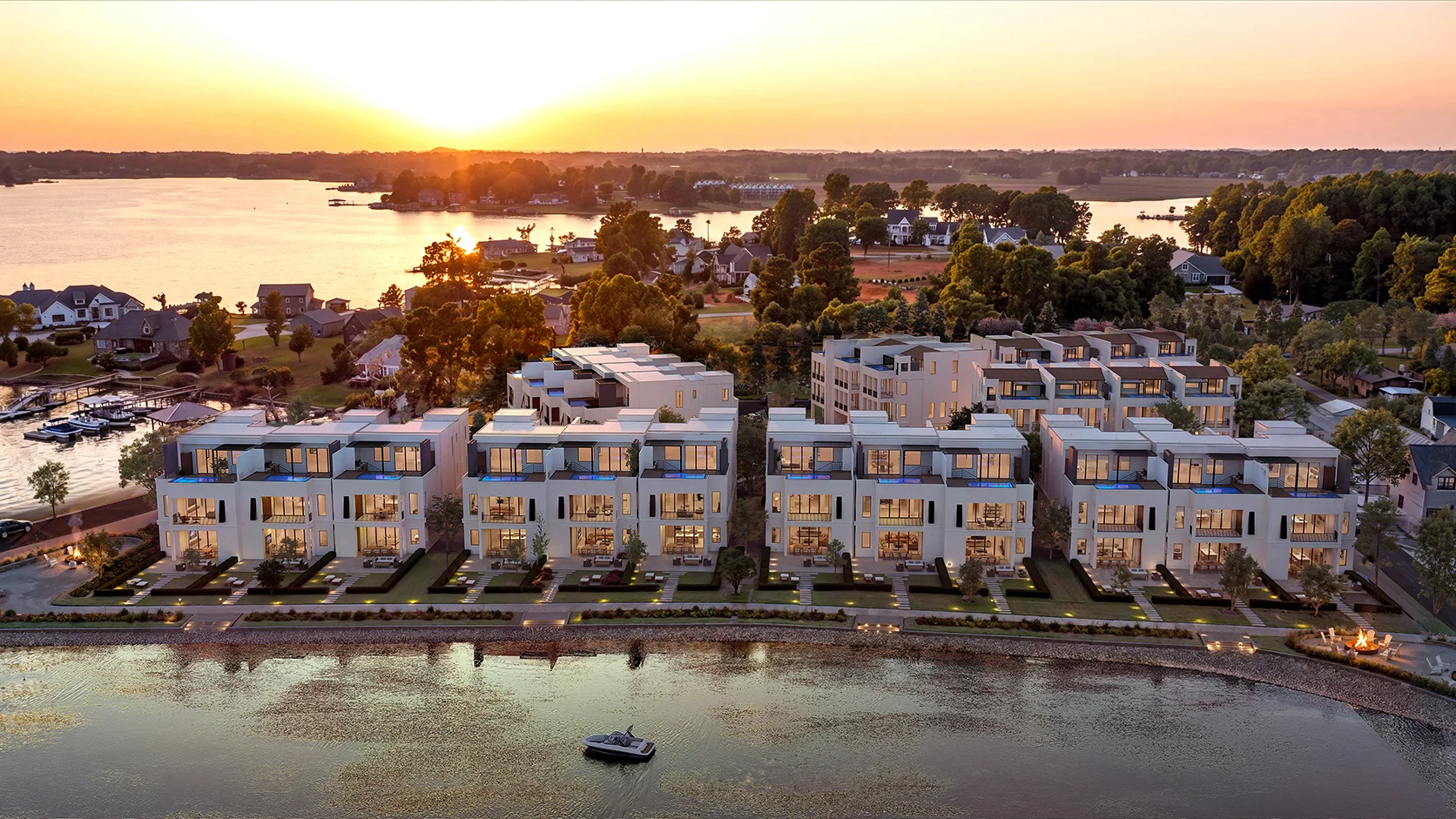 Modern Lake Norman townhomes at sunset, overlooking the water with a boat and surrounding trees, creating a serene and picturesque scene.